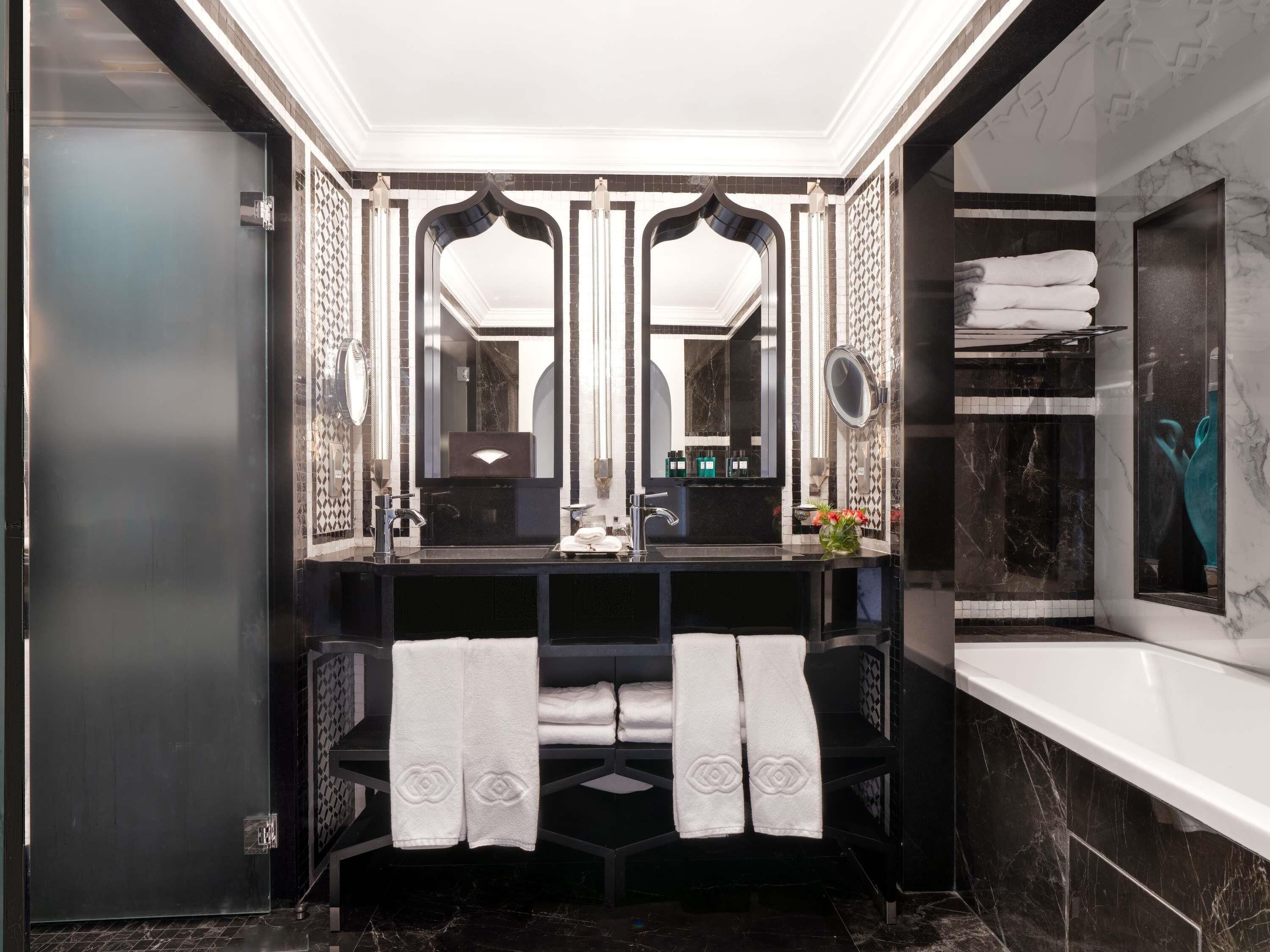 A modern bathroom with a black vanity, two mirrors, a sink, and a bathtub.