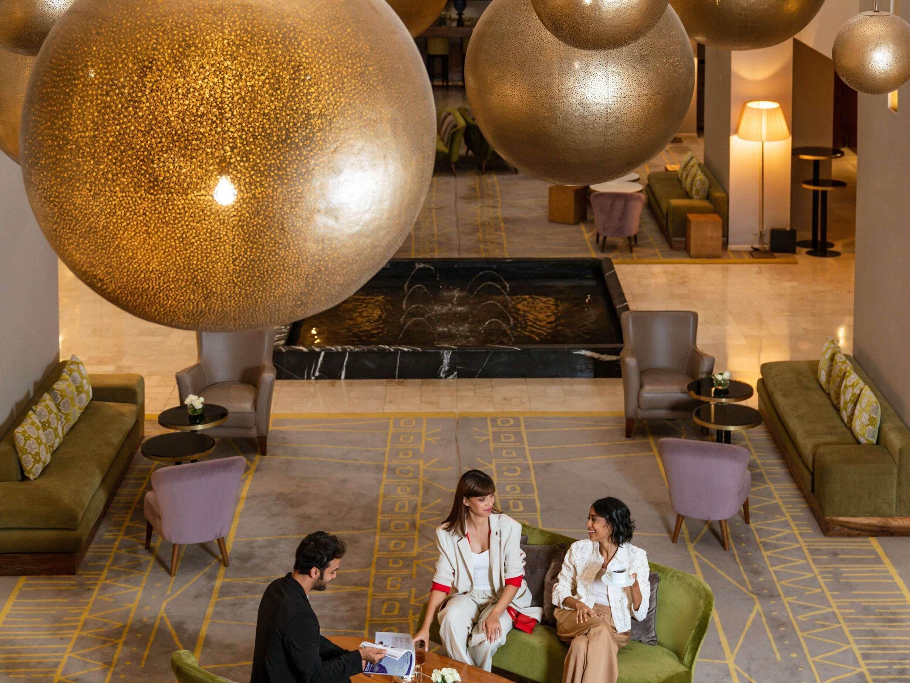 A spacious lobby with a central water feature, seating areas, and large decorative spheres.