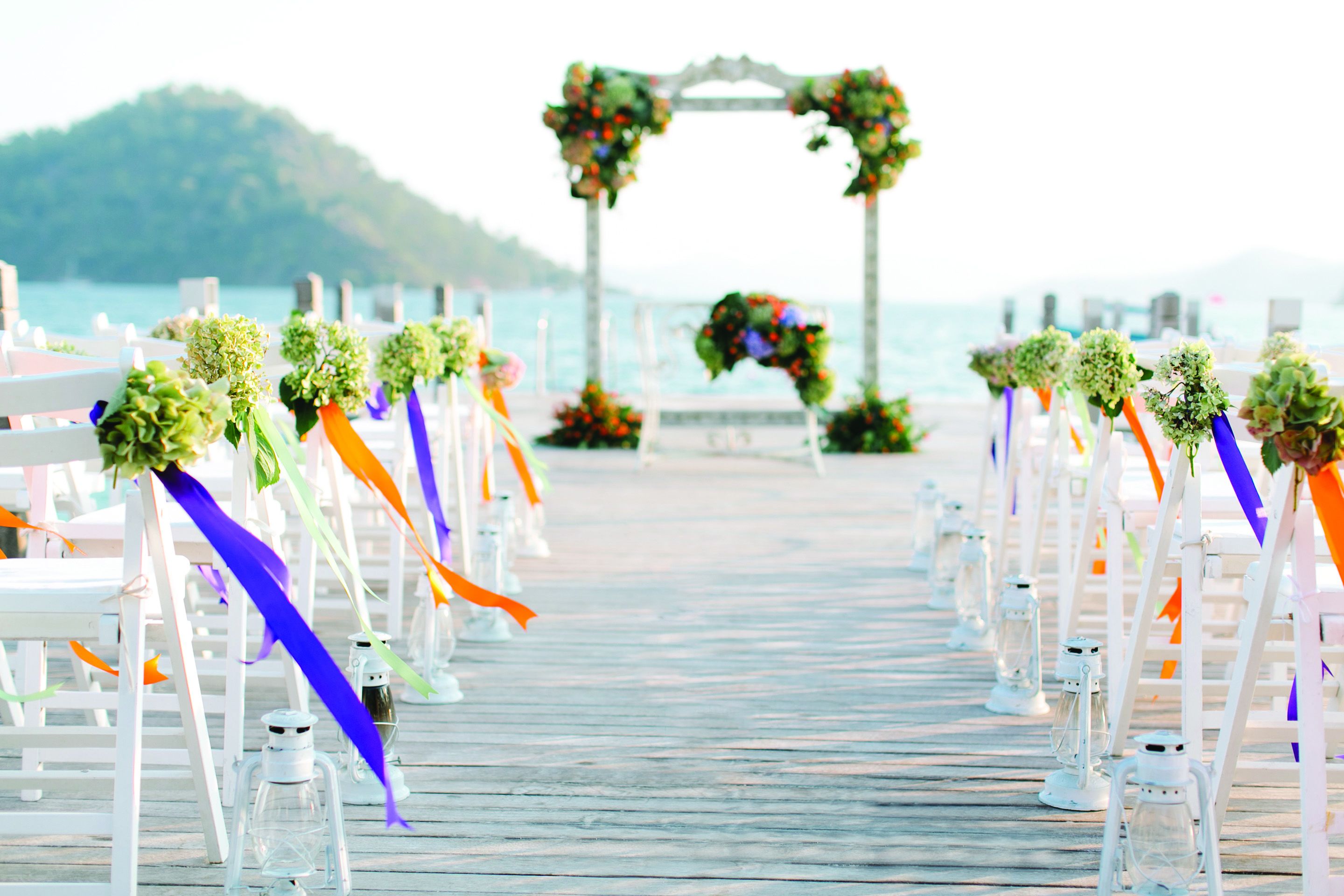 Un muelle de madera que lleva a un arco de flores y follaje para una boda.