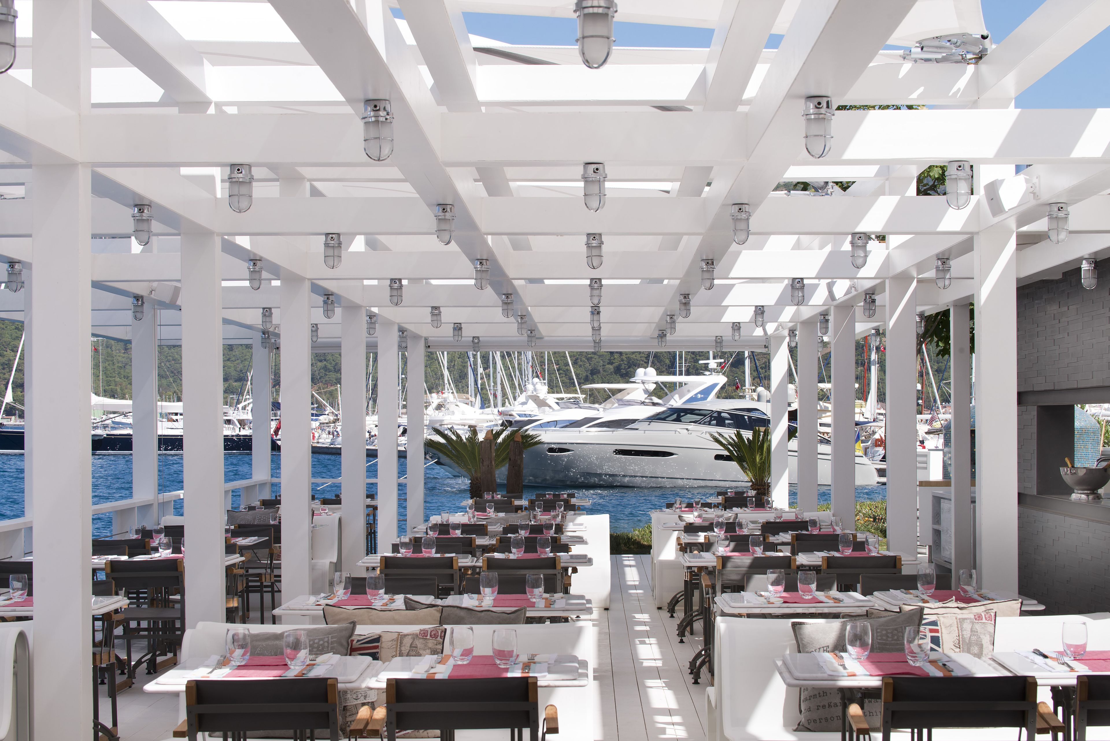 Een restaurant met terras, met uitzicht op een jachthaven vol boten.