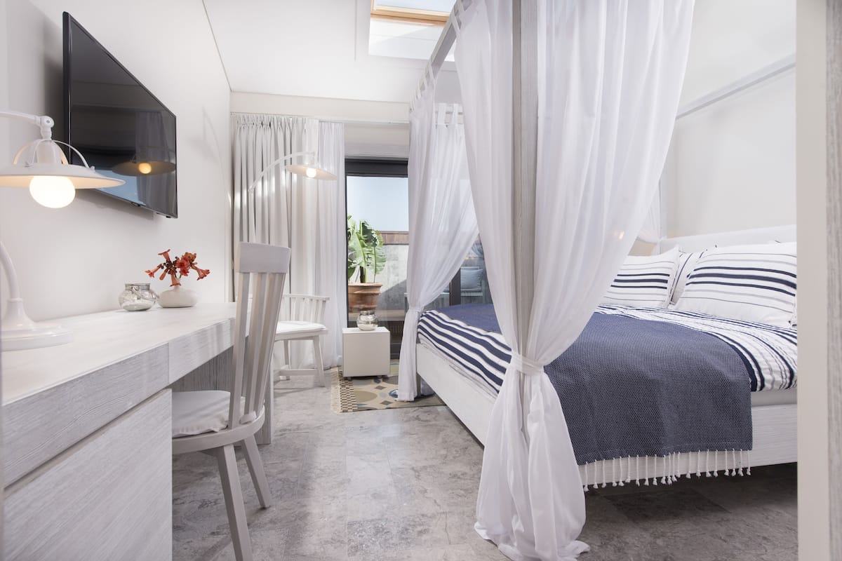 Ein modernes Schlafzimmer mit einem Bett, einem Nachttisch und einem an der Wand befestigten Fernseher.