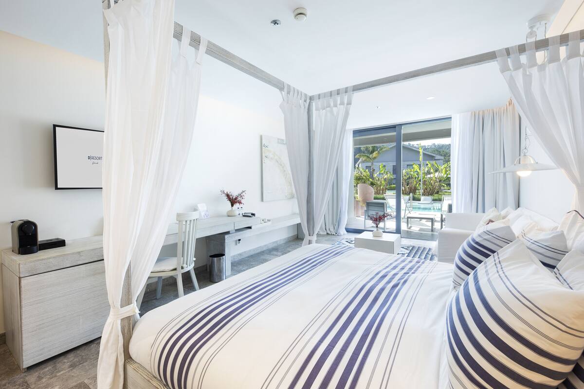 Ein modernes Schlafzimmer mit einem großen Bett, einem Nachttisch, einem Schreibtisch und Blick ins Freie.