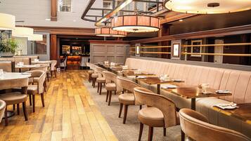 A restaurant with wooden flooring, leather booths, and pendant lighting.