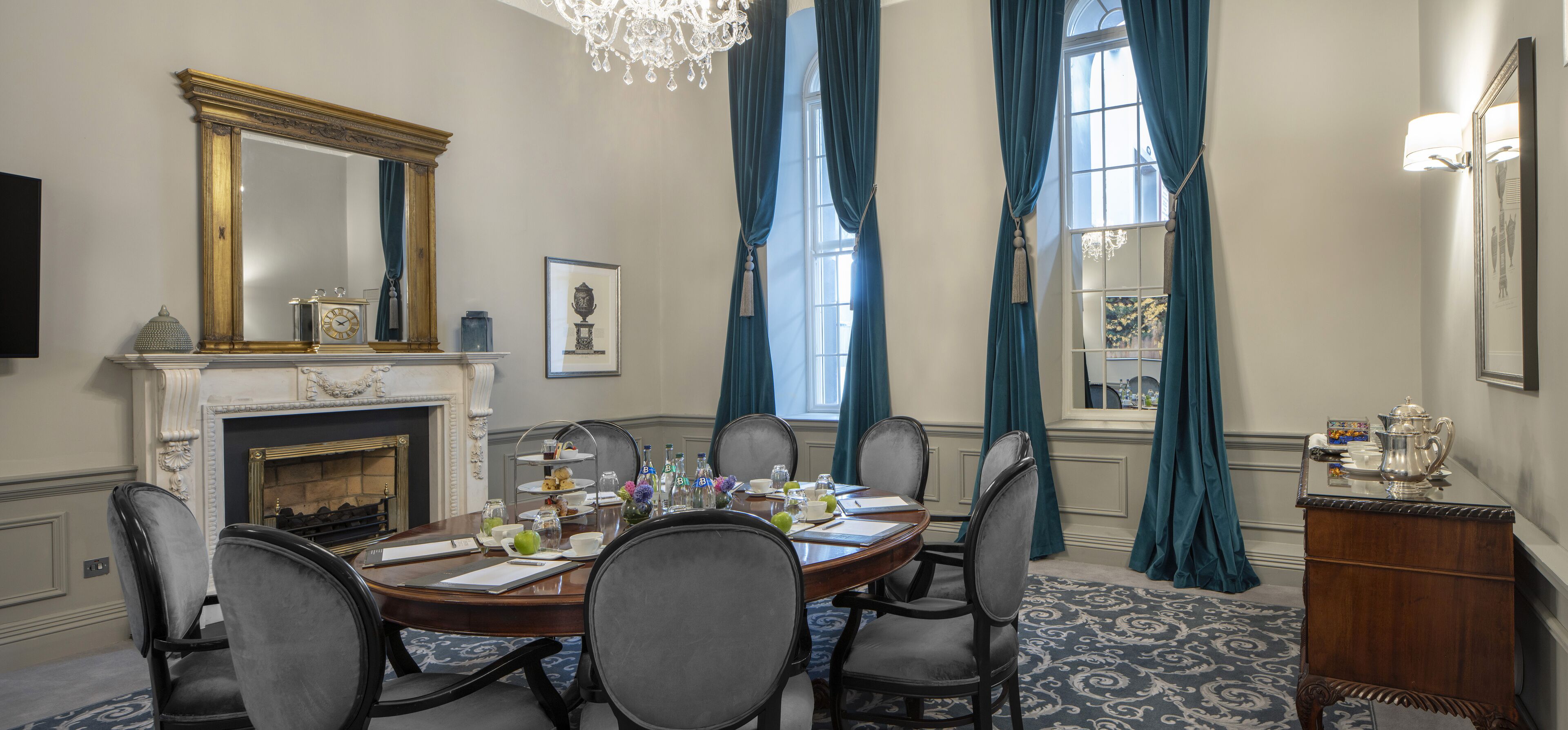 Une salle à manger élégante, dotée d’une cheminée, d’un lustre et d’un grand miroir.