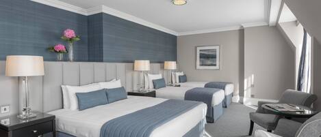 Habitación de hotel con dos camas, zona de estar y vistas a la ciudad.