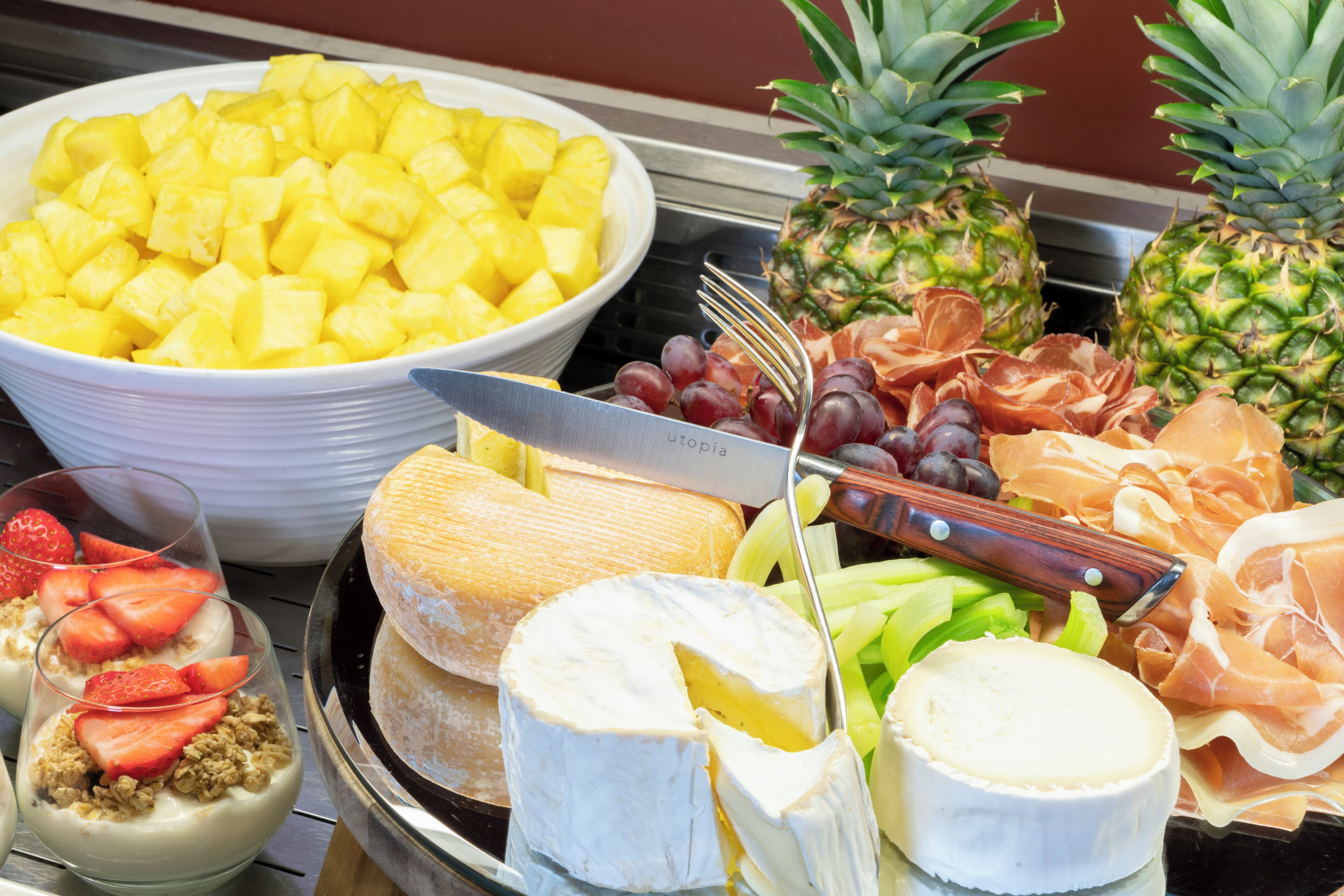 A buffet with various cheeses, fruits, and meats.