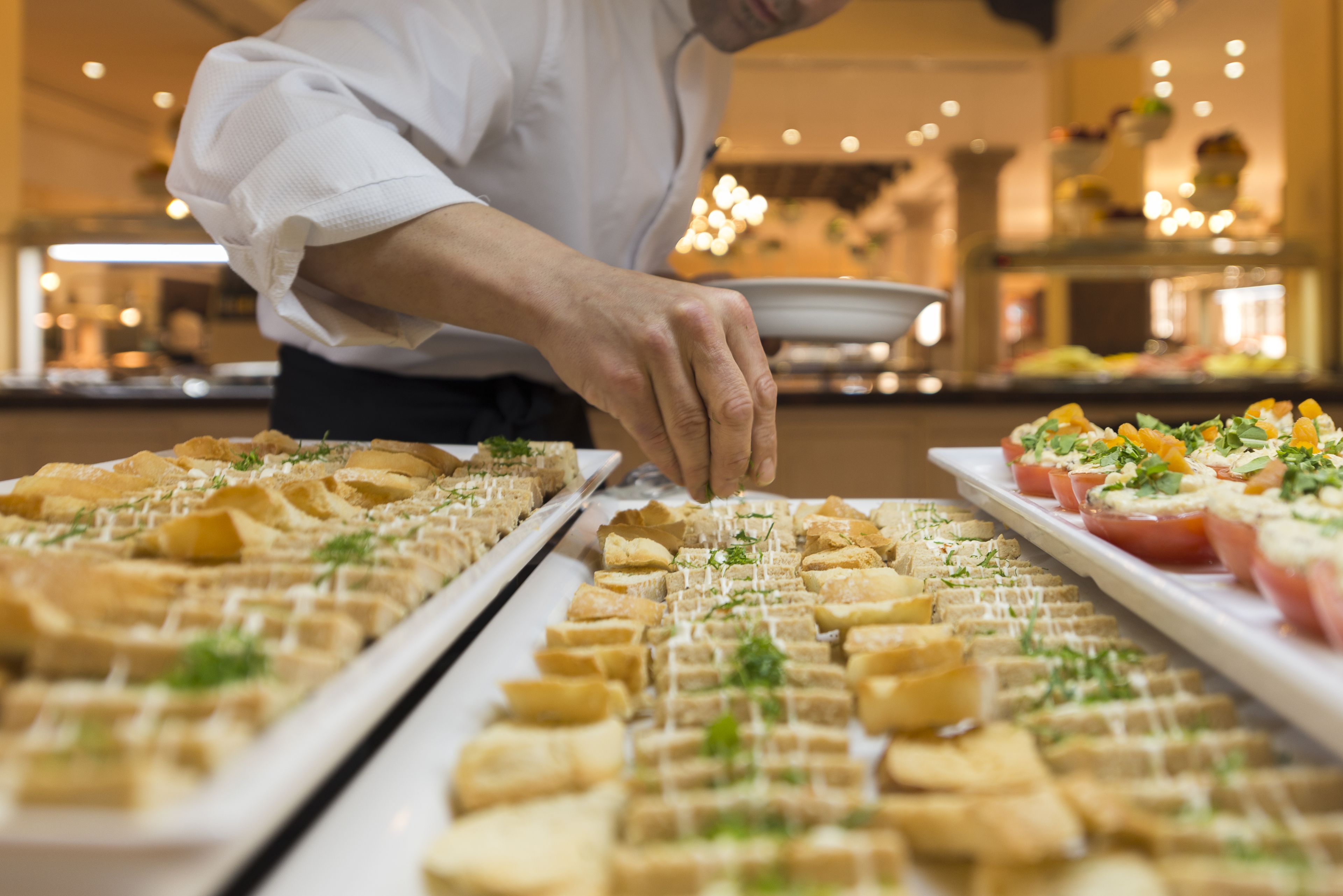Een buffetopstelling met diverse gerechten en een persoon die gasten bedient.