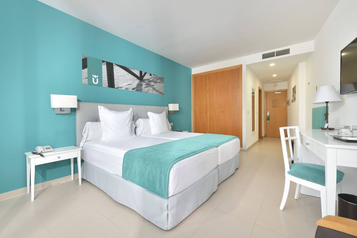 A modern hotel room with a large bed, a desk, and a chair.