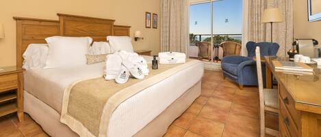 A hotel room with a large bed, a desk, a chair, and a view of the outdoors.