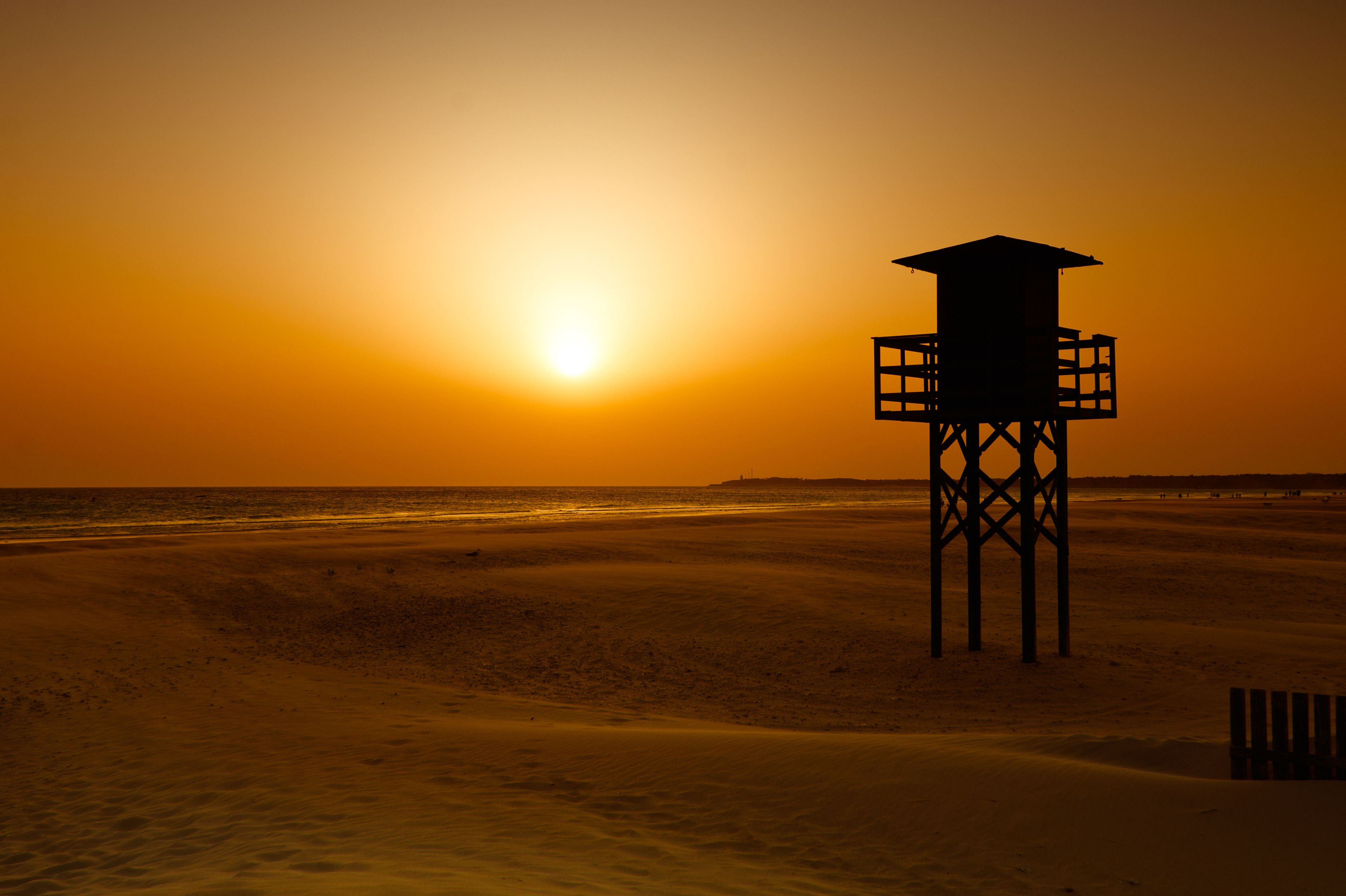 A lifeguard tower on a beach at sunset.