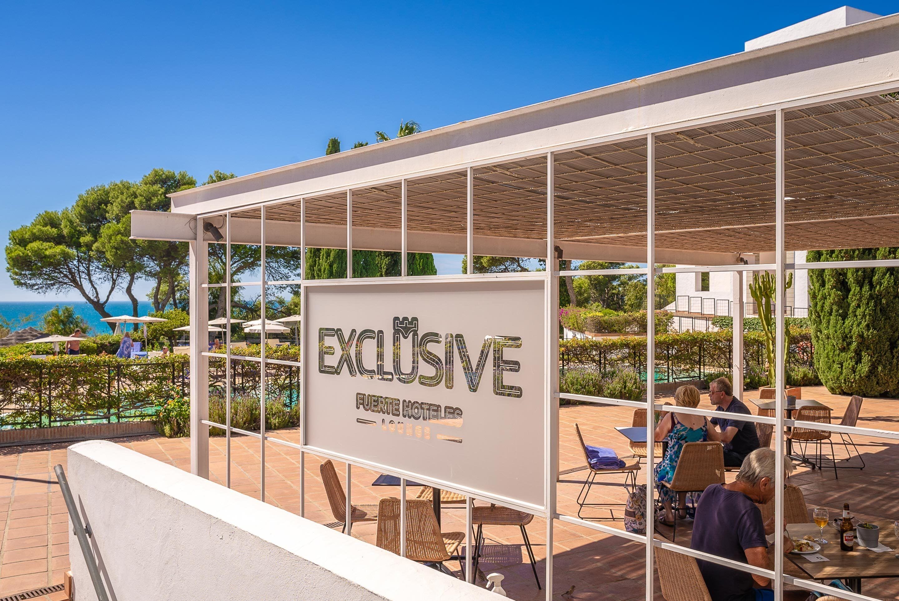 Uma área de estar externa com uma placa que diz 'EXCLUSIVE FUERTE HOTELES'.