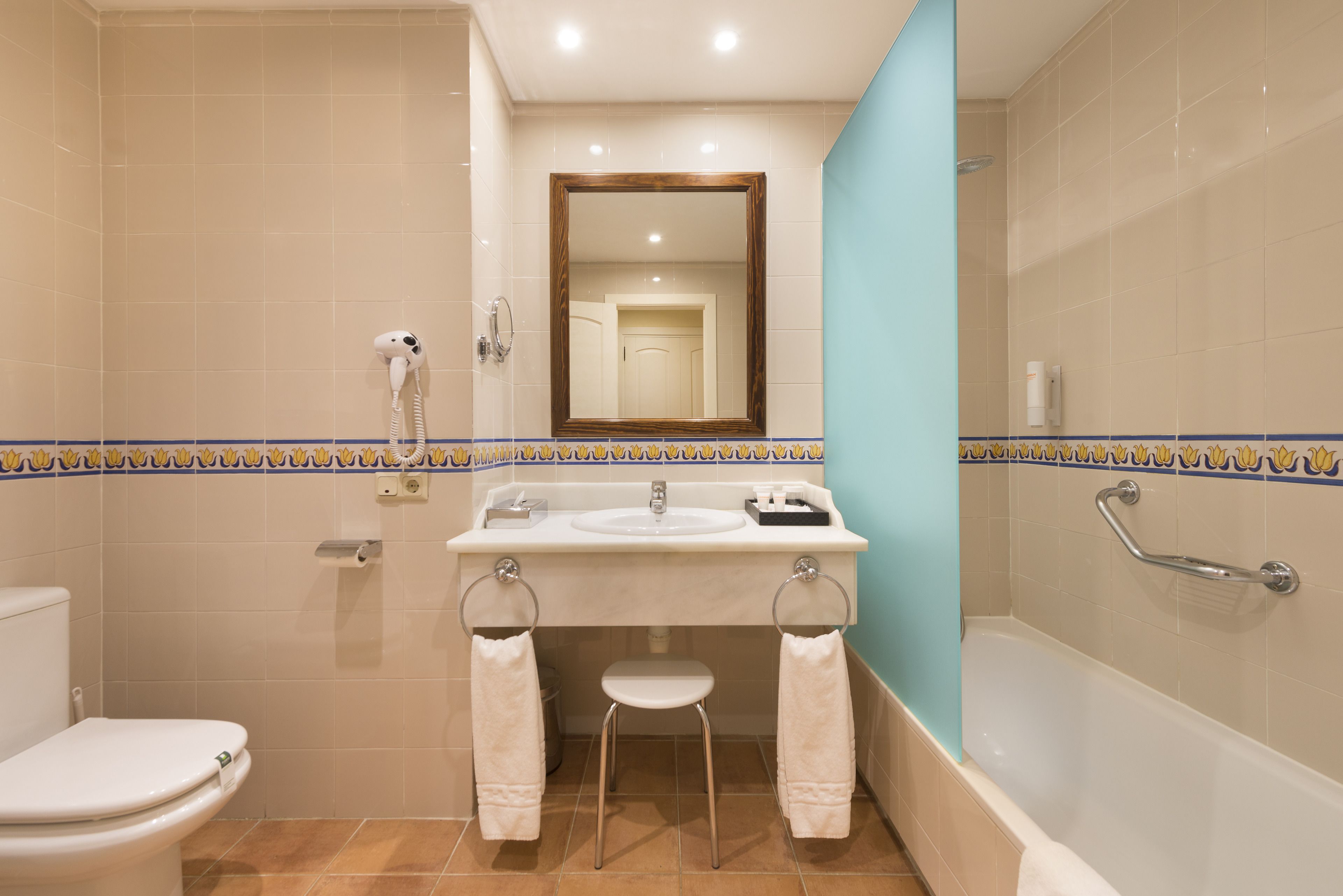 A bathroom with a toilet, sink, mirror, and bathtub.