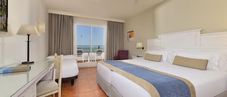 Una camera d'albergo con un letto, una scrivania, una sedia e vista mare dalla finestra.