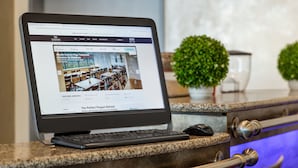 Um laptop sobre um balcão exibindo um site de hotel com comodidades como uma coleção especial e um refúgio perfeito para escapar do caos.