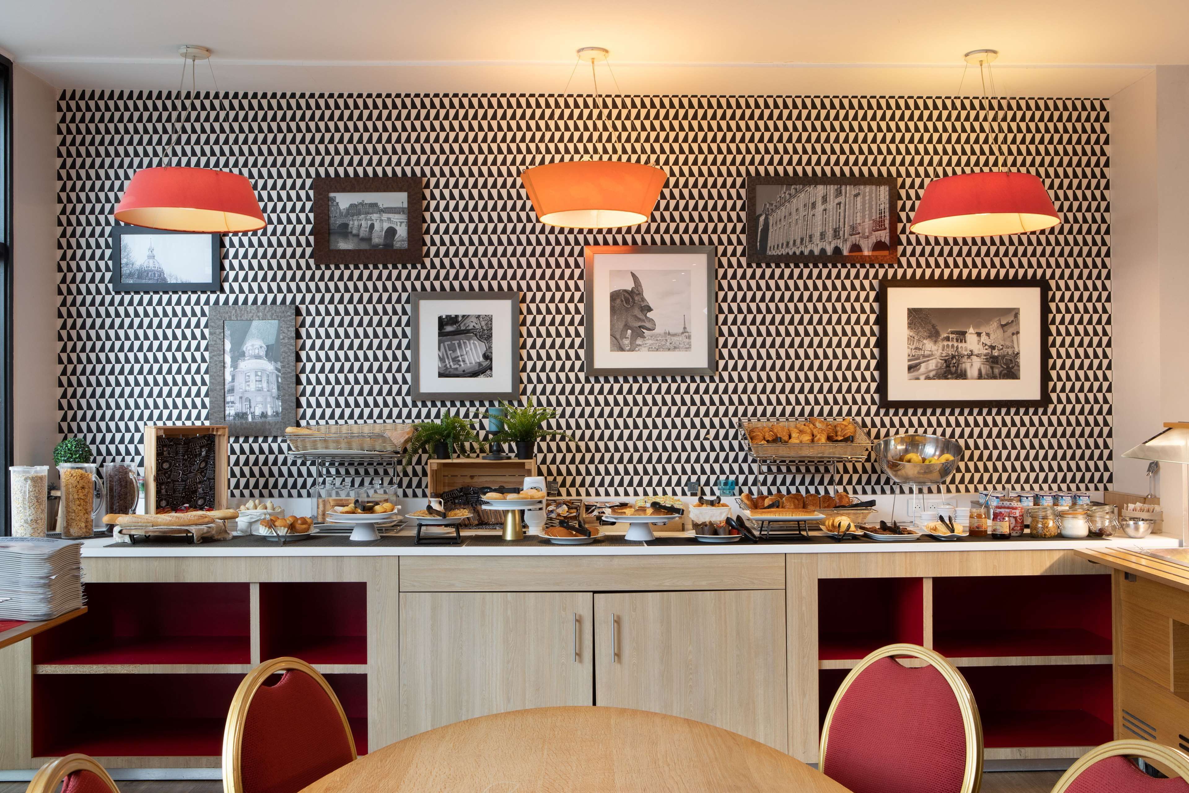 A modern kitchen with a patterned backsplash, pendant lights, and a variety of food items displayed on the counter.