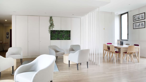 Ein modernes Interieur mit Essbereich, Sofas und einer vertikalen Grünwand.