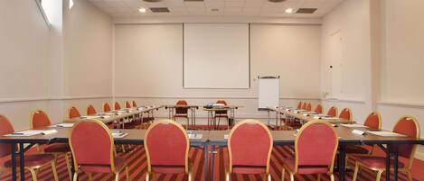 A conference room with a long table, red chairs, and a whiteboard.