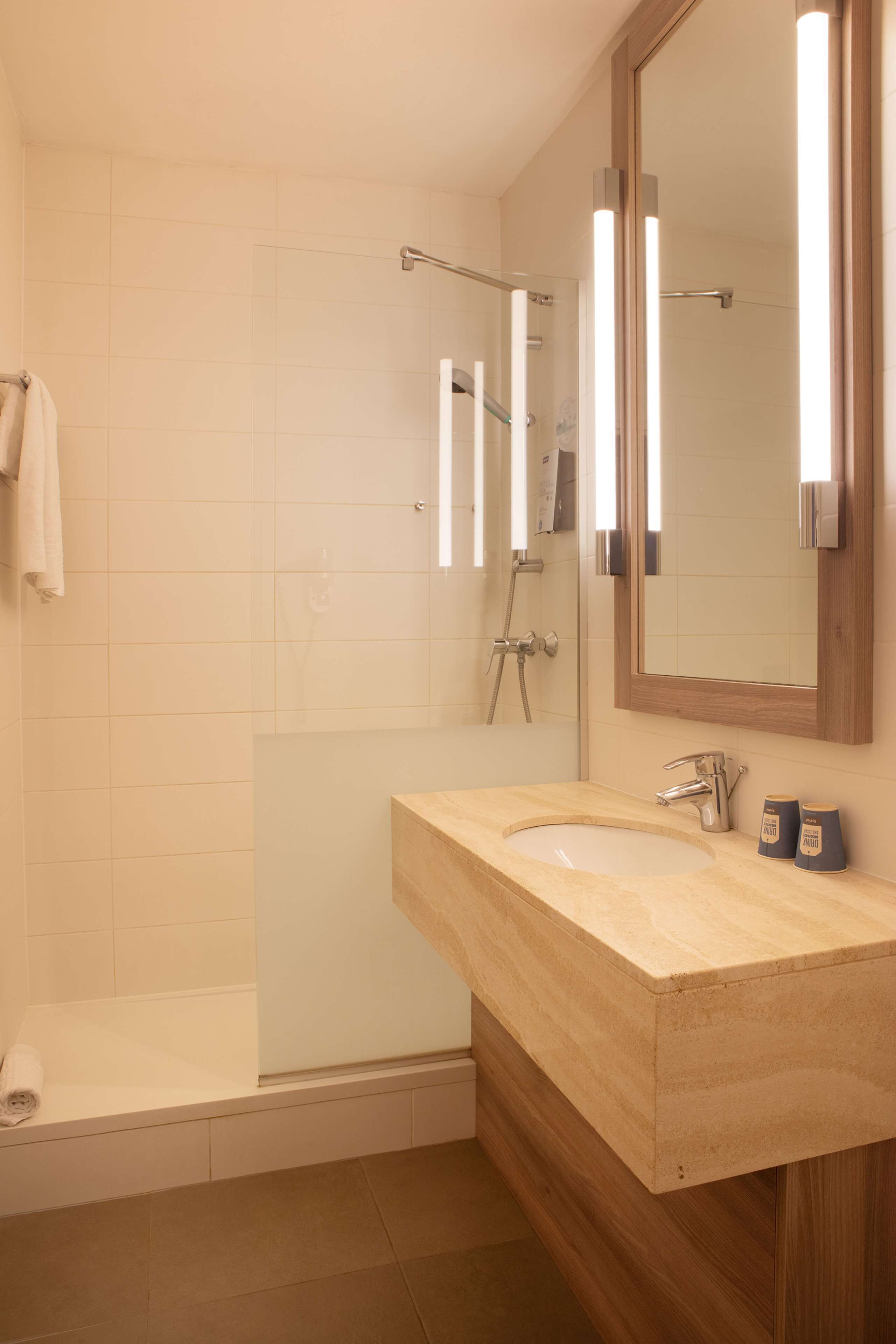 A bathroom with a sink, mirror, and shower.