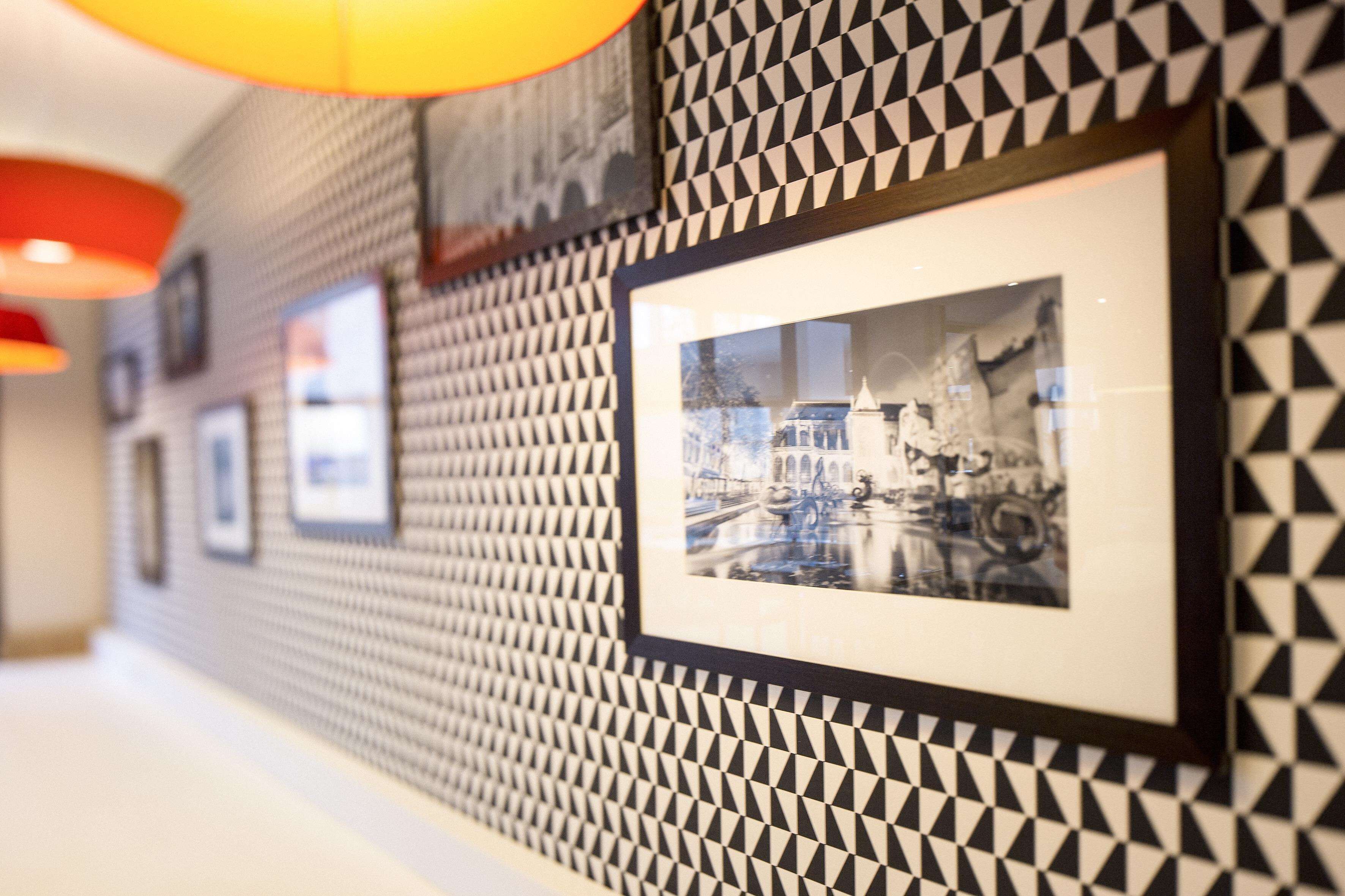 Un couloir aux murs ornés de motifs et où sont accrochées des photographies encadrées.