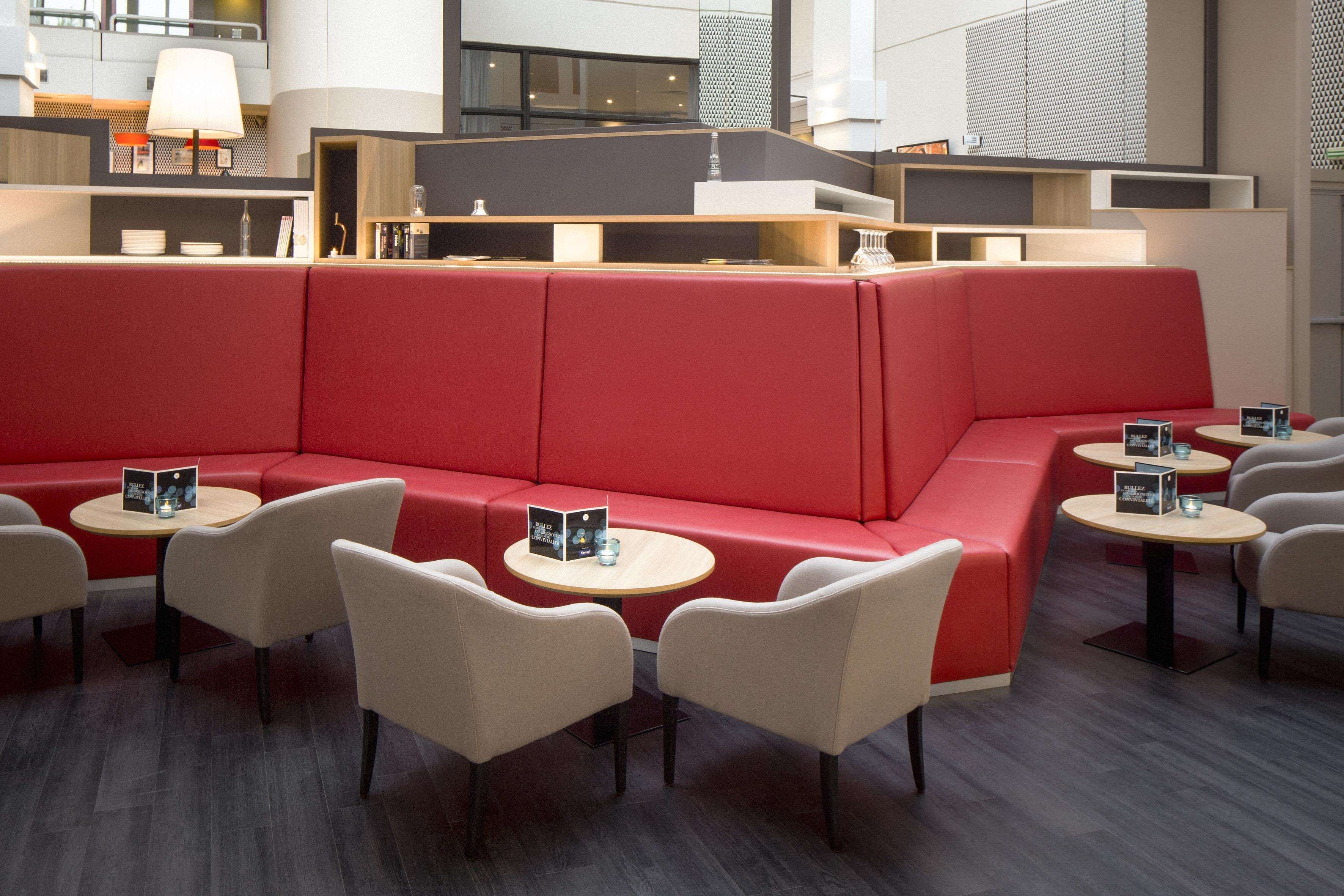 A modern lounge area with red seating, round tables, and a contemporary design.