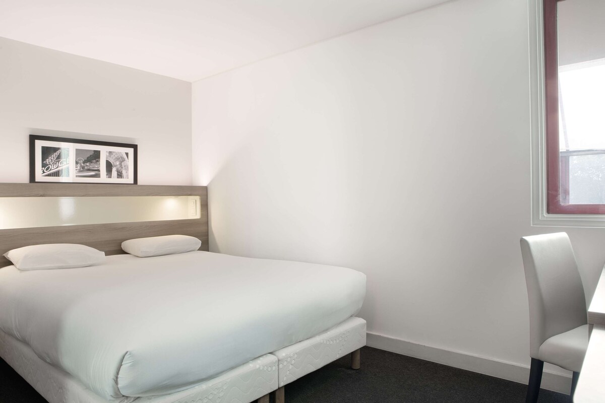 Habitació d'hotel amb llit, escriptori i finestra.