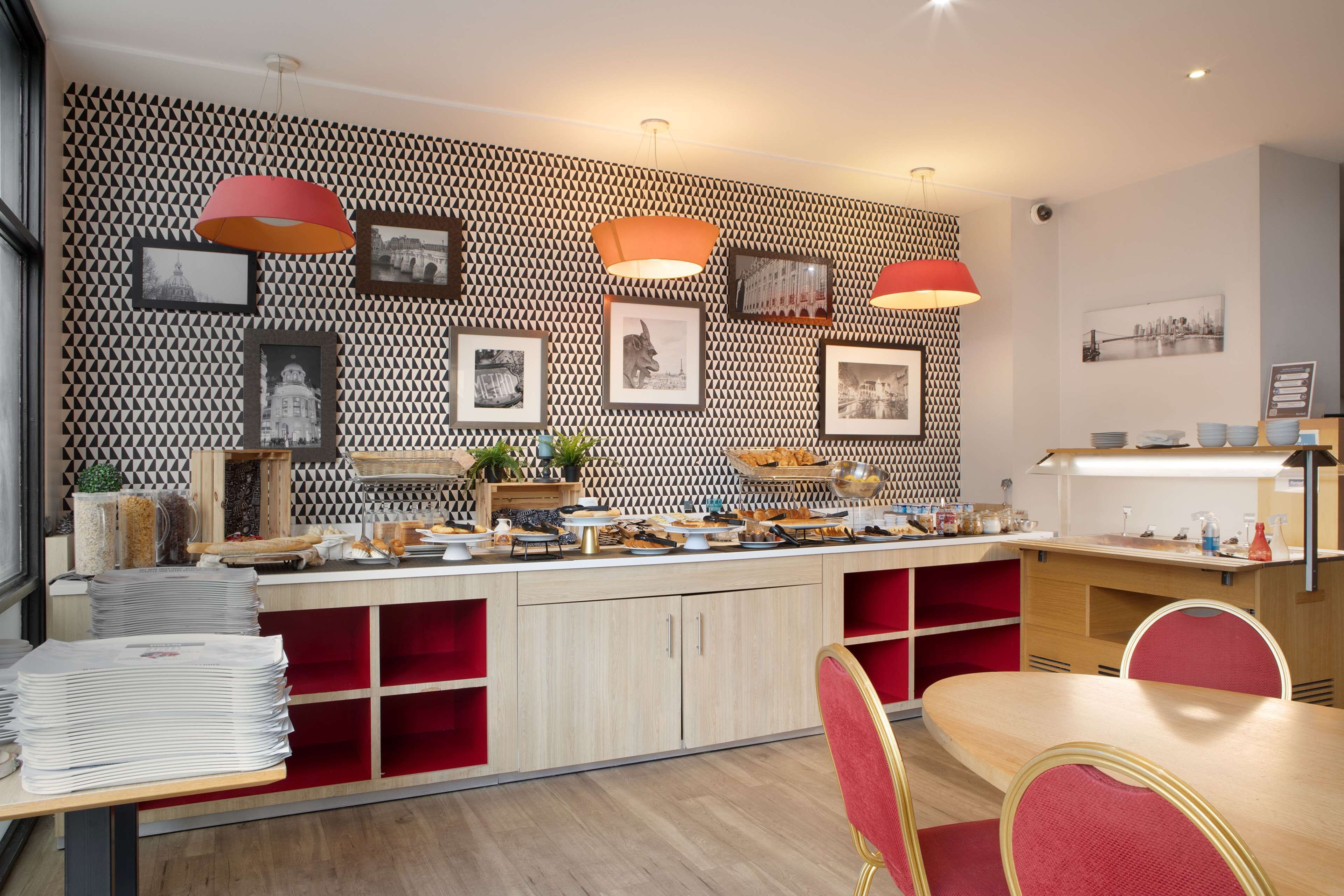 Un espace repas moderne avec un mur à motifs, des chaises rouges et un buffet.