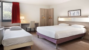 Ein Hotelzimmer mit zwei Betten, einem Schreibtisch, einem Stuhl, einem Kleiderschrank und einem Fenster mit rotem Vorhang.