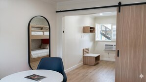 A room with bunk beds, a desk, a chair, a round table, and a window with a view of a staircase. - Americas Best Value Inn & Suites Anaheim Convention Center (Anaheim)
