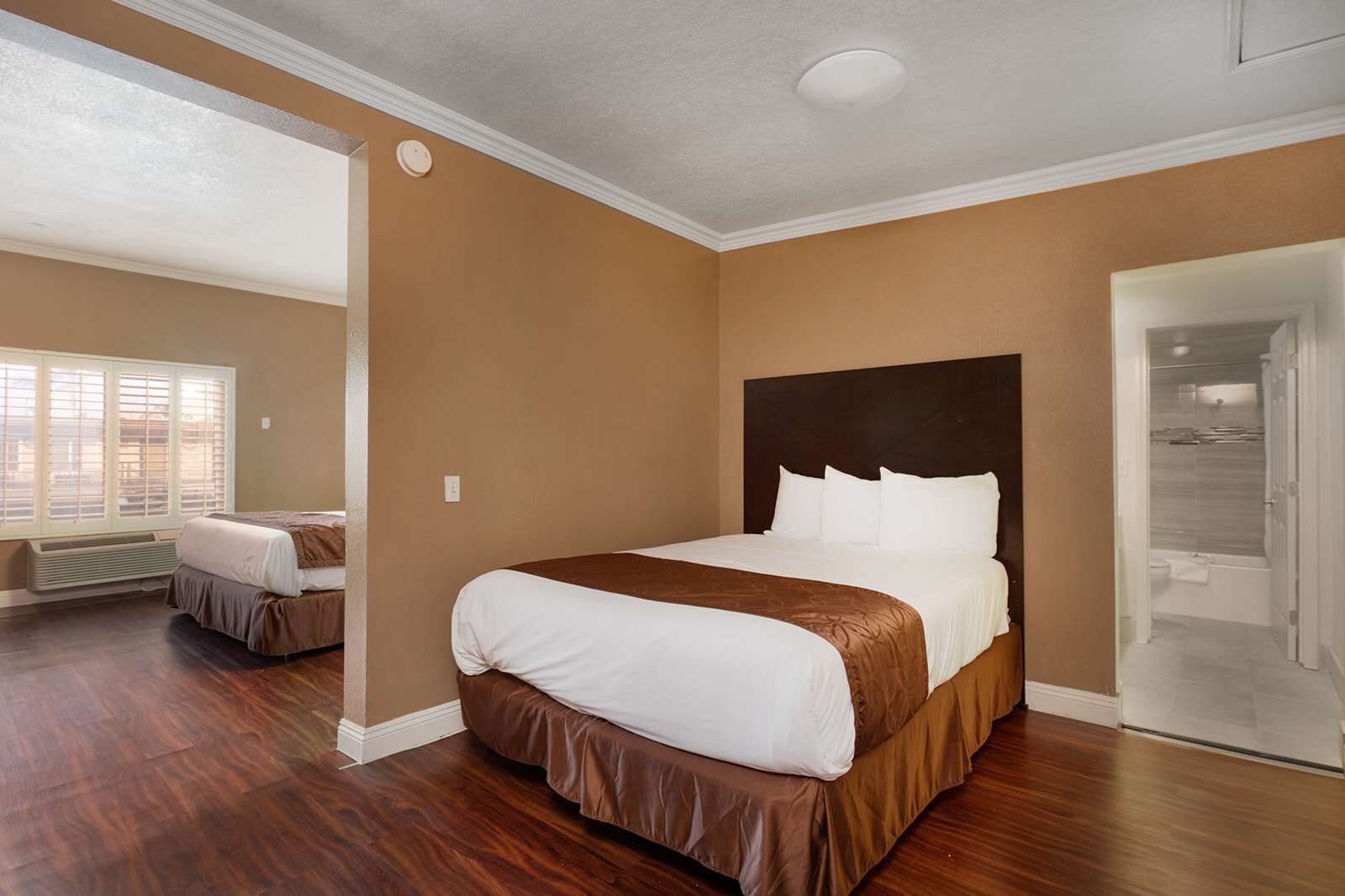 A hotel room with a large bed, a walk-in closet, and a bathroom with a shower and toilet.