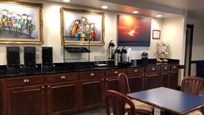 A modern kitchen with wooden cabinets, a black countertop, and a dining area with striped upholstered chairs. - Homestead Apart-Hotel (Pleasantville)