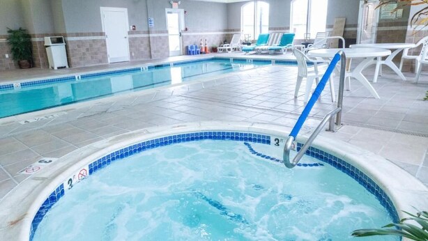 An indoor swimming pool with a hot tub, lounge chairs, and a tiled floor. - Homestead Apart-Hotel (Pleasantville)