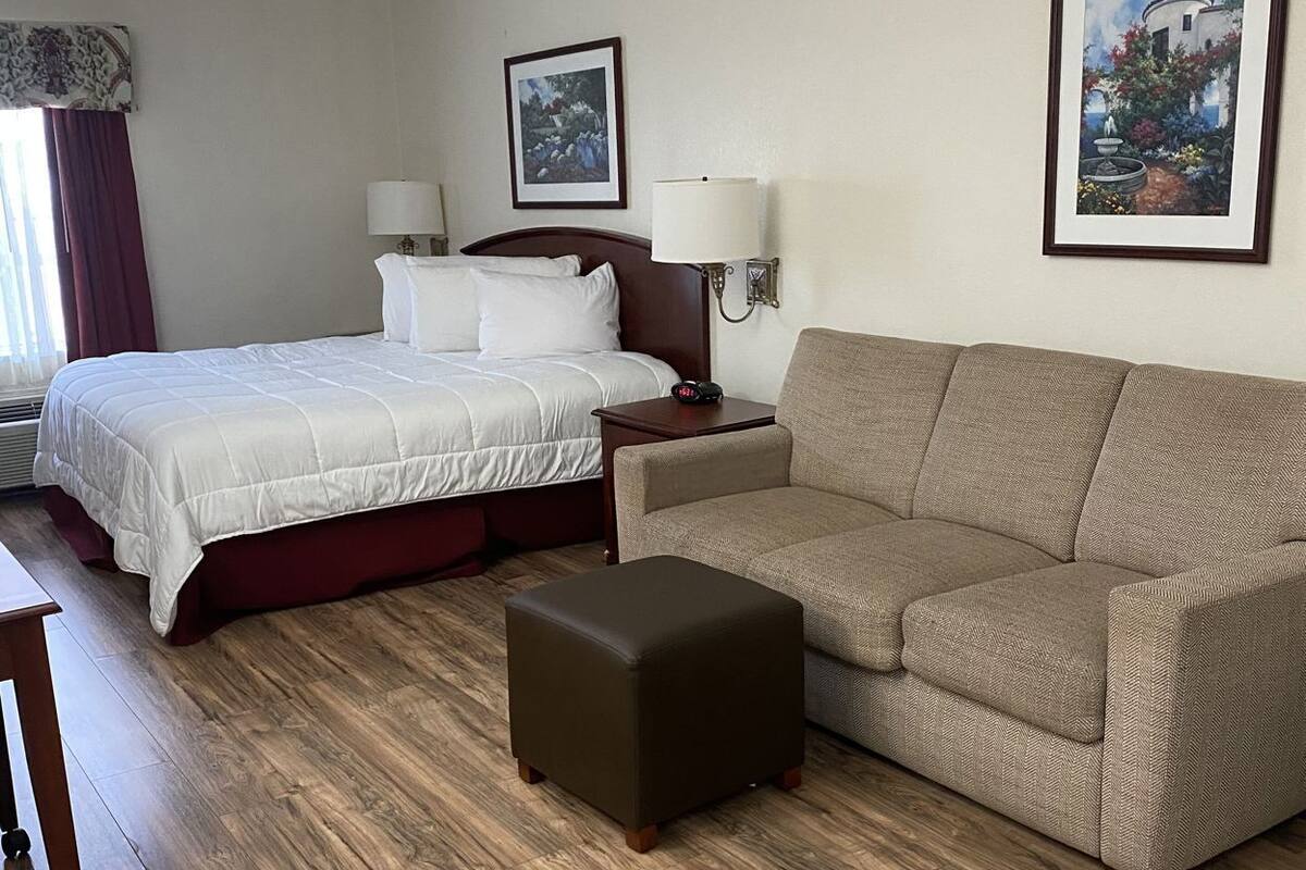 Ein Hotelzimmer mit Bett, Sofa, Nachttisch und Lampe.