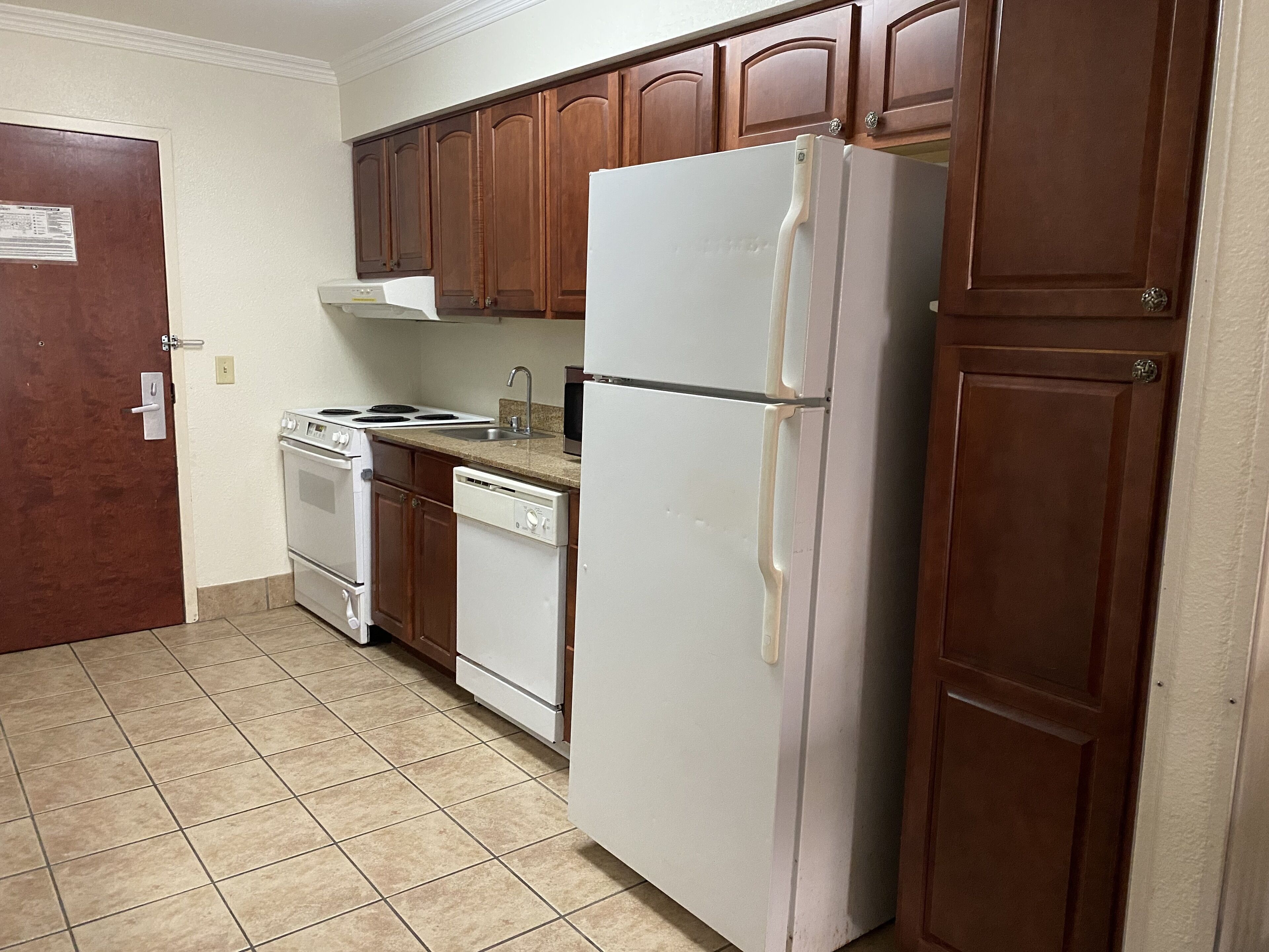 Una cocina con armarios de madera, un refrigerador blanco, una estufa y un lavavajillas.