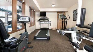 Een sportschool met cardioapparatuur, een loopband en gewichten.
