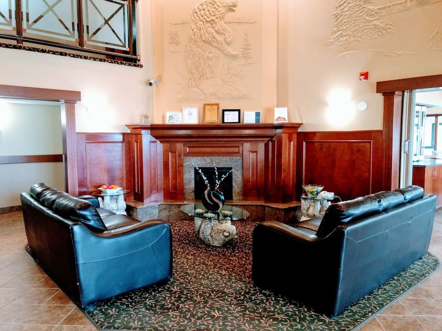 A lobby with two leather sofas, a fireplace, and a decorative wall mural.
