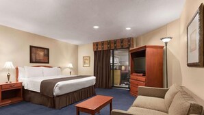 Una habitación de hotel con cama, escritorio, silla, televisor y armario.