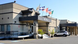 Un hotel con fachada moderna, una rampa para accesibilidad y varias banderas.