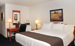 A hotel room with a bed, two bedside lamps, a desk with a chair, a microwave, and a painting on the wall. - Hotel Le Mirage Blainville (Blainville)