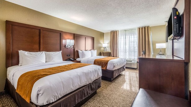 A hotel room with two beds, a wooden headboard, a flat-screen TV, a desk, and a large window with curtains. - Comfort Inn & Suites Dayton North (Dayton)