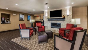 A hotel lobby with red upholstered chairs, a fireplace, and a flat-screen TV mounted on the wall. - Comfort Inn & Suites Dayton North (Dayton)