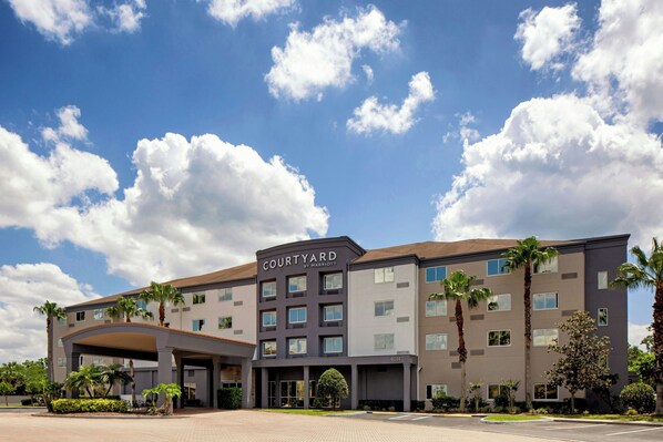 A Courtyard by Marriott hotel with a modern design, featuring multiple floors, a covered entrance, and a landscaped courtyard.