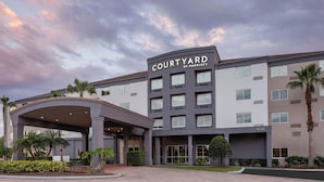 A Courtyard by Marriott hotel with a modern design, featuring a covered entrance and multiple floors.