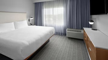 Habitación de hotel con una cama grande, televisor de pantalla plana, escritorio y ventana con cortinas.