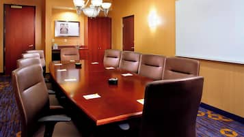 A conference room with a large wooden table, leather chairs, a whiteboard, and a carpeted floor.