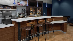 A modern bar area with a long counter, bar stools, and a variety of liquor bottles.
