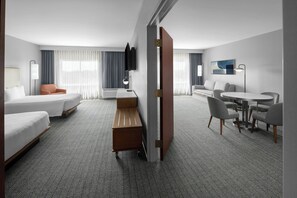 A hotel room with a bed, a desk, a chair, a small table, and a TV.
