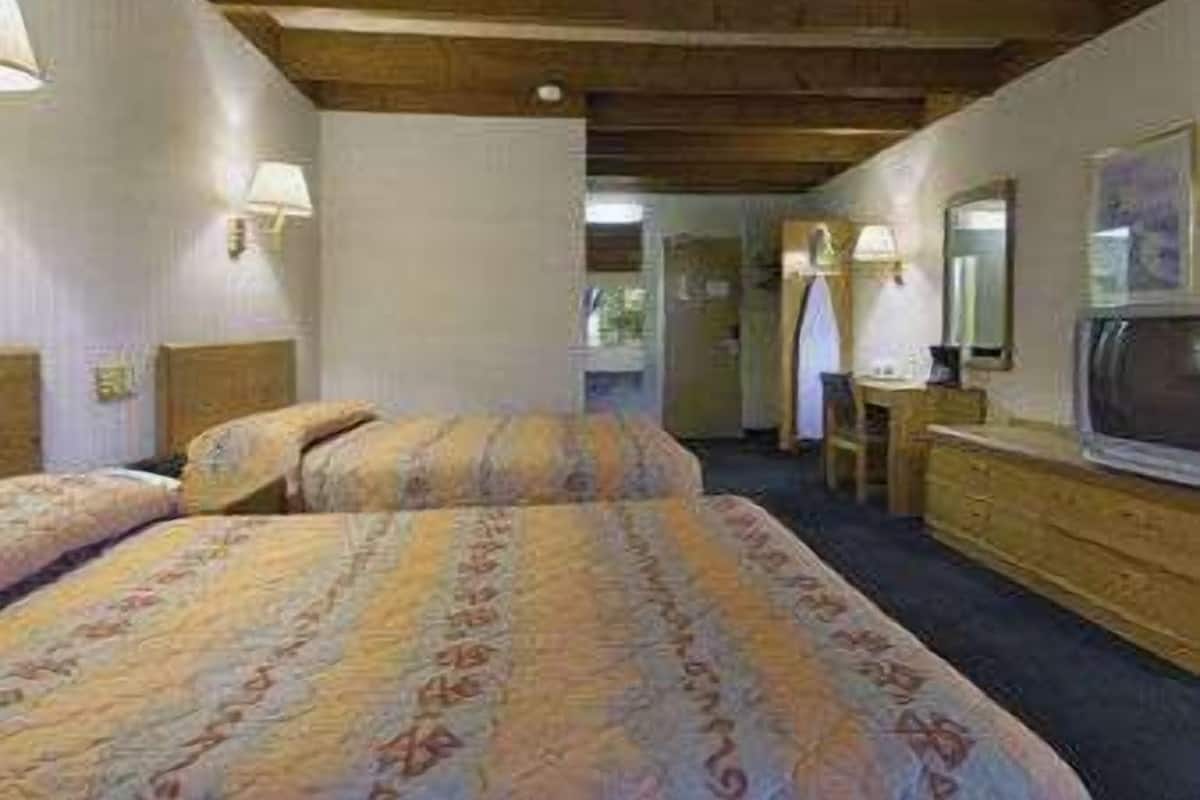 A hotel room with a bed, a dresser, a mirror, and a television.