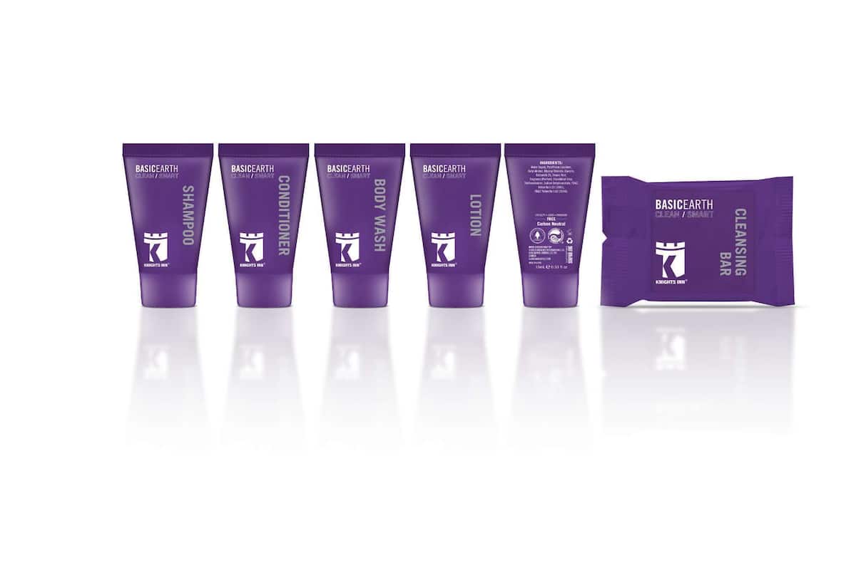 A row of purple tubes labeled 'BASICEARTH' with different product names like 'SHAMPOO', 'CONDITIONER', 'BODY WASH', 'LOTION', and a 'CLEANSING BAR'.