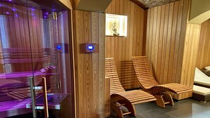 A sauna room with wooden walls, a glass sauna, and two wooden loungers. - Green Garden Hotel (Prague)