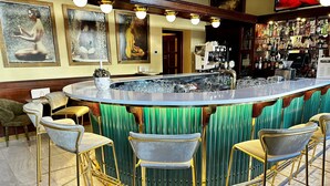 A bar area with a round counter, bar stools, and a green decorative panel. - Green Garden Hotel (Prague)